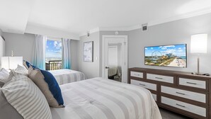 Une chambre d’hôtel avec deux lits, une télévision, une commode et un balcon donnant sur la ville.