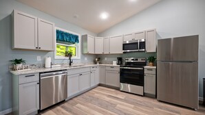 Una cocina moderna con electrodomésticos de acero inoxidable, armarios de color gris claro y piso de madera.