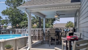 Ein überdachter Patio-Bereich mit Pool, Gartenmöbeln und einer Pergola.