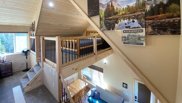 Un dormitorio estilo loft con escalera de madera, literas y zona de comedor con mesa y sillas.