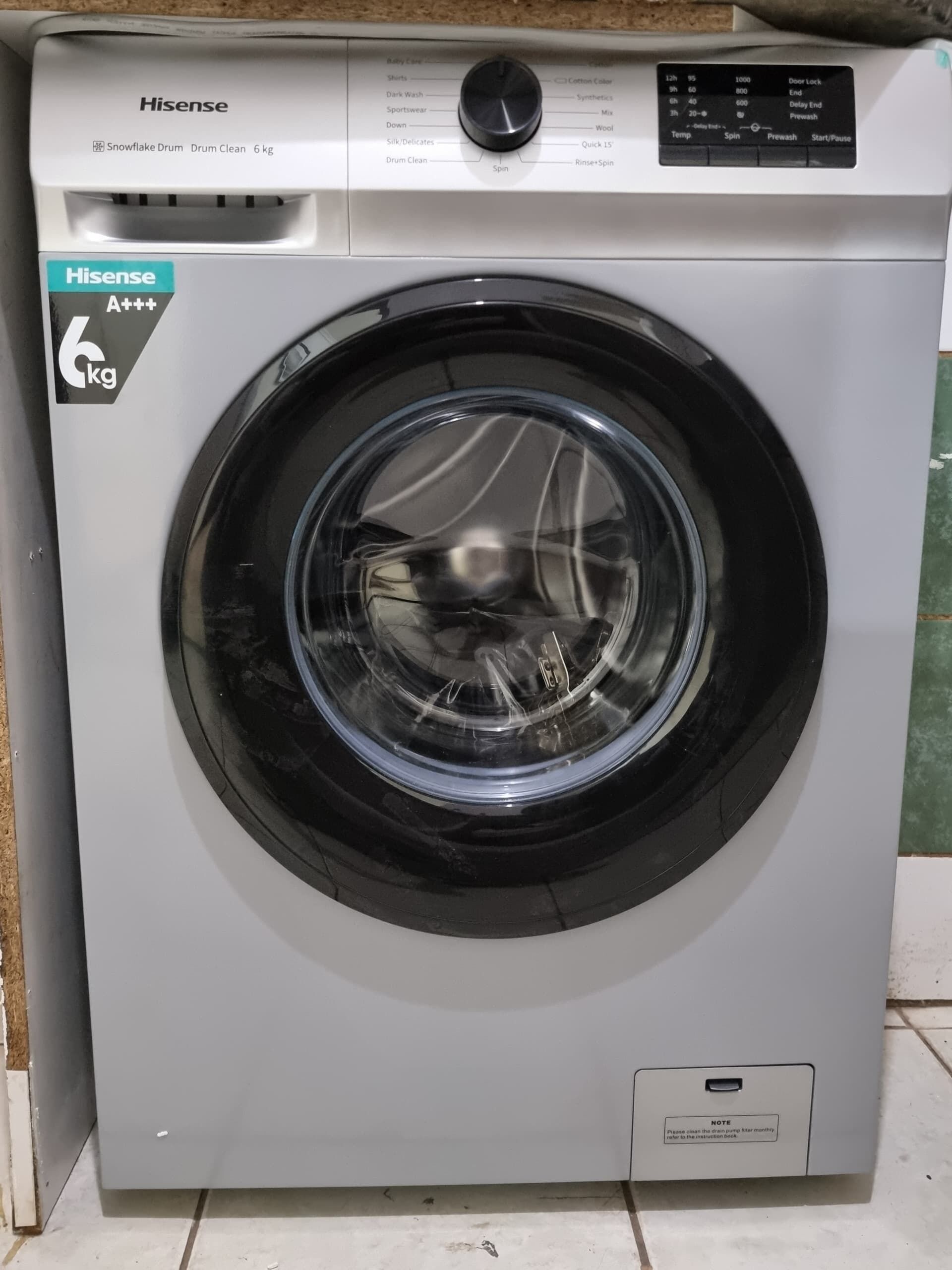 A Hisense 6kg front-loading washing machine with a control panel, a digital display, and a note about the pump filter.