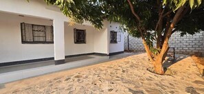 A building with a sandy ground, white walls, and windows with black frames. - Eagle Weavers Nest (Livingstone)