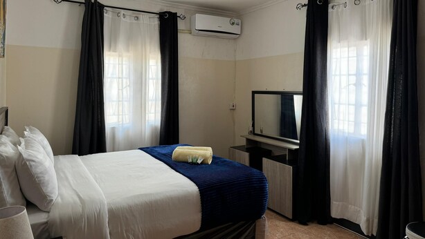 A hotel room with a bed, a TV, and curtains. - Eagle Weavers Nest (Livingstone)