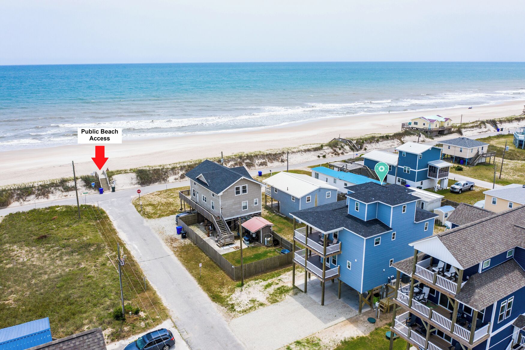 A coastal residential area with houses near the beach, featuring a public beach access point.