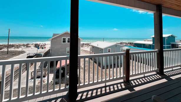 Une propriété située en bord de mer, dotée d’un porche abrité, d’une piscine et de maisons de plage en arrière-plan.