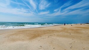 Une vaste plage de sable fin, avec des vagues douces et un ciel dégagé.