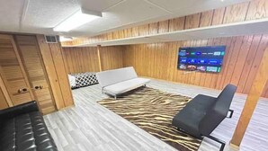 A room with a zebra-patterned rug, a white sofa, a black chair, and wooden paneling on the walls. - PROMO 10% WEEKLY AND 15% MONTHLY!
Spacious & Quaint Home Game Room LOTS of Beds! (wheaton)