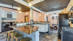 Een moderne keuken met een centraal eiland, barstoelen, een ingebouwde wasmachine en droger, en een groot fornuis.