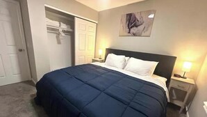 A bedroom with a bed, bedside tables, a closet, and a painting on the wall.