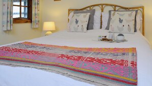 A neatly made bed with a colorful blanket, a bedside table with a lamp, and a window with curtains. - 1 bedroom accommodation in Betws Y Coed (Betws Y Coed)