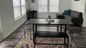 A modern living room with a dining table, a sofa, and a chandelier.
