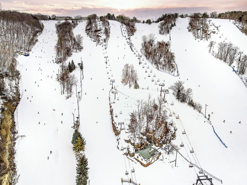 Eine Skipiste mit mehreren Skiliften und einem kleinen Gebäude am Fuß.