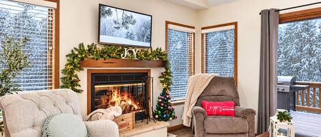 A cozy living room with a fireplace, a Christmas tree, and a comfortable seating area.