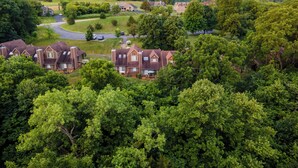 A residential area with multiple houses surrounded by lush greenery and hills in the background. - Wooded 2 King BR, Woodburning Fireplace, Near Trails, Golf, Spa (Galena)