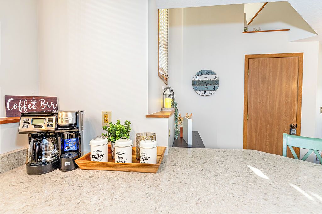 Een keuken met een koffieapparaat, een dienblad met koffie, een klok en een houten deur.
