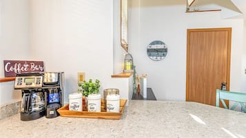 Een keuken met een koffieapparaat, een dienblad met koffie, een klok en een houten deur.