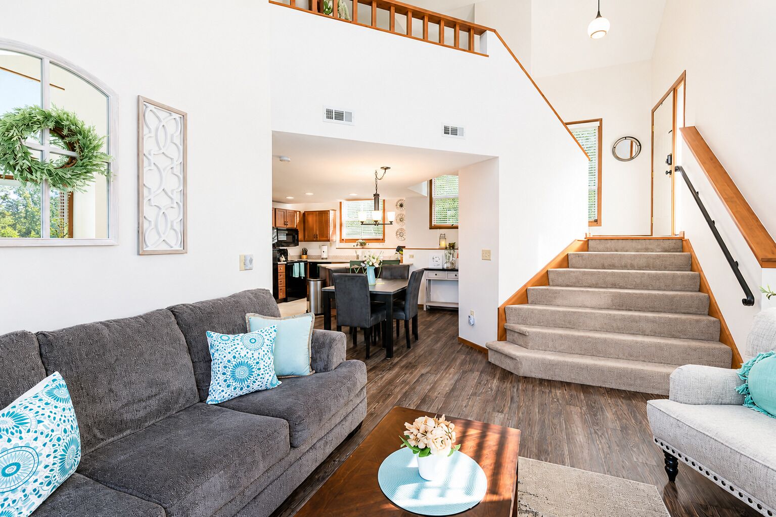 A modern living room with a grey sofa, a coffee table, and a staircase leading to an upper level.