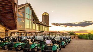 A row of golf carts parked in front of a building with large windows and a silo in the background. - Wooded 2 King BR, Woodburning Fireplace, Near Trails, Golf, Spa (Galena)