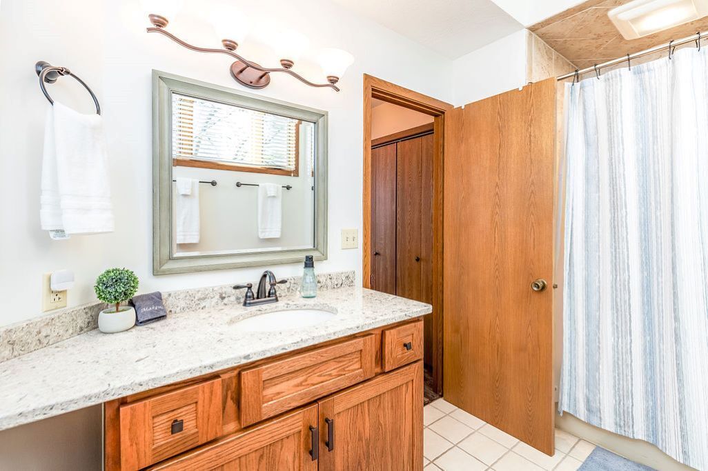 A bathroom with a wooden vanity, a large mirror, and a shower curtain.