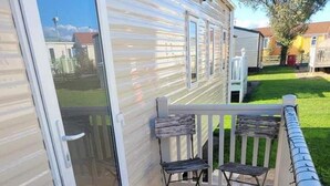 Una terraza techada con dos sillas y una puerta que da a un patio trasero.