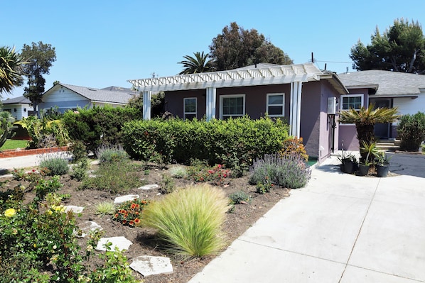A residential house with a front garden, a driveway, and a clear blue sky.