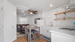 Une cuisine moderne avec des armoires blanches, une cuisinière à gaz et un ventilateur de plafond.