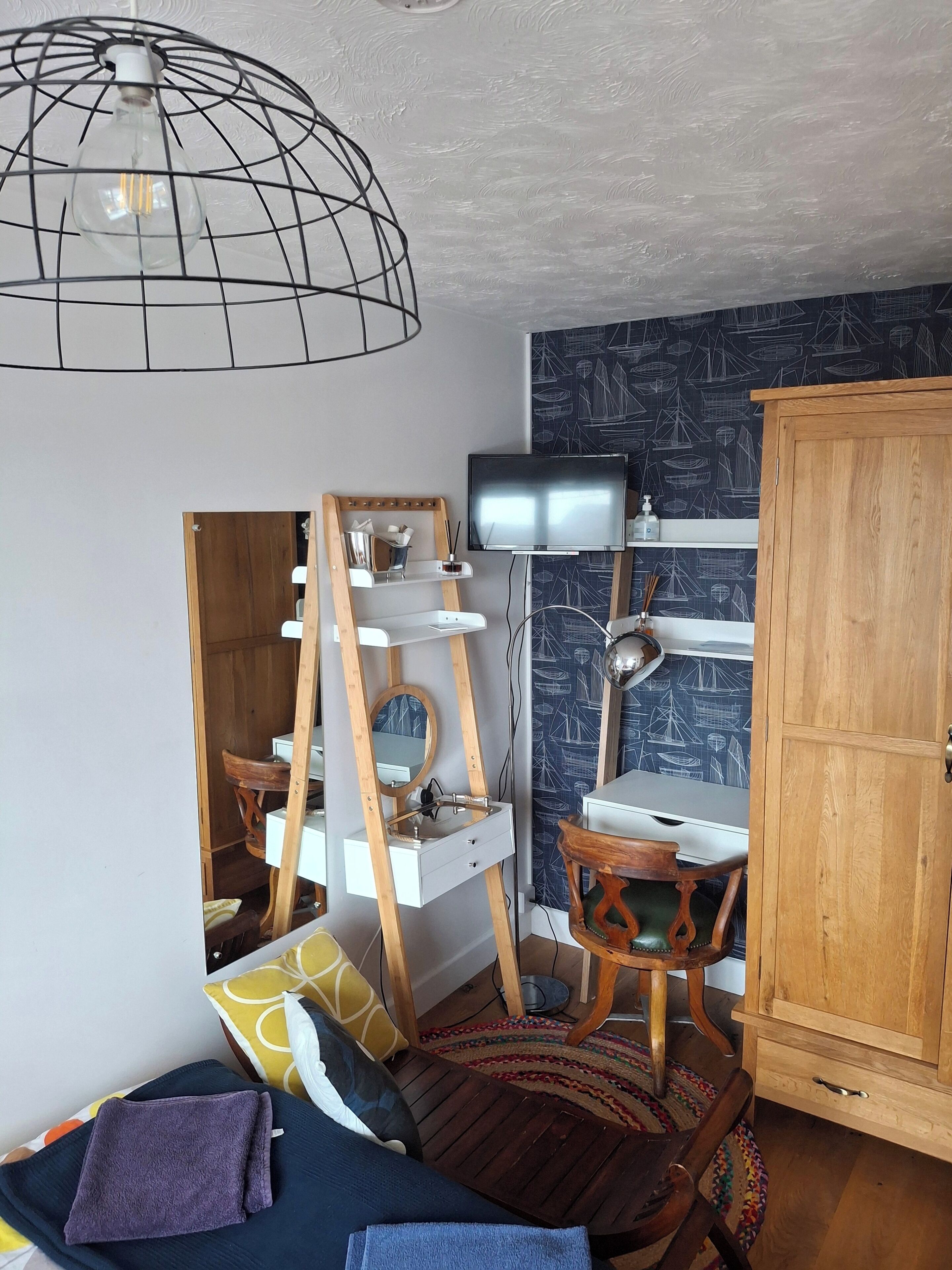 Une pièce comprenant un meuble en bois, un téléviseur, un miroir et un luminaire suspendu.