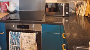A modern kitchen with blue cabinets, a black stove, a microwave, and a toaster. - Marina View, South Facing Balcony Sunny Apartment (East Cowes)