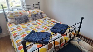 A bed with a colorful polka dot bedspread, a blue towel, and a Japanese-style pillow. - Marina View, South Facing Balcony Sunny Apartment (East Cowes)