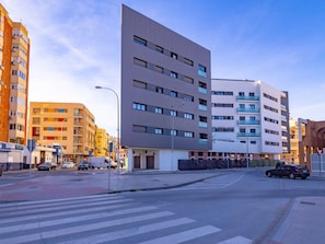 Eine moderne Stadtstraße mit mehrstöckigen Gebäuden, einer Fußgängerampel und parkenden Autos.