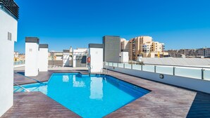 Una piscina en la azotea con un cielo azul despejado al fondo.