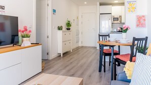 Una cocina moderna con comedor, muebles blancos y un televisor de pantalla plana en la encimera.