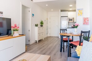 A modern kitchen with a dining area, white cabinetry, and a flat-screen TV on the counter. - Cubo's La Union Apartment Pool Optional Parking / urban / air conditioning / free wifi (Málaga)