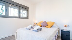 Habitación de hotel con cama, dos mesitas de noche, una ventana y vistas a edificios.