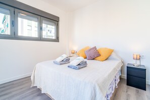 A hotel room with a bed, two bedside tables, a window, and a view of buildings outside. - Cubo's La Union Apartment Pool Optional Parking / urban / air conditioning / free wifi (Málaga)