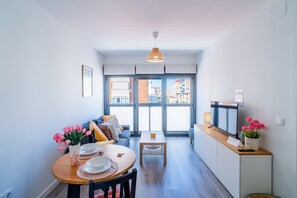 Un appartement moderne comprenant un coin repas, un canapé, une télévision et offrant une vue sur la ville grâce à de grandes fenêtres.