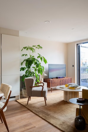 Uma sala de estar moderna com uma planta grande, uma TV de tela plana e uma área de estar aconchegante.