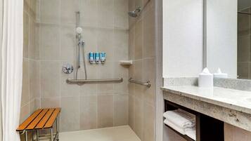 A modern bathroom with a shower, a bench, and a vanity with a mirror.