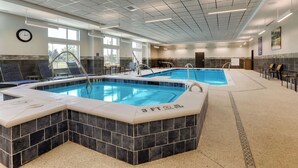 An indoor swimming pool with a 3 FT step, lounge chairs, and a clock on the wall. - Drury Plaza Hotel Savannah Pooler (Pooler)