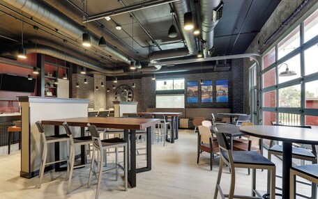 A modern cafe with exposed ductwork, a brick wall, and large windows.