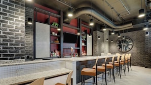 A bar area with a long counter, multiple stools, and a large clock on the wall. - Drury Plaza Hotel Savannah Pooler (Pooler)
