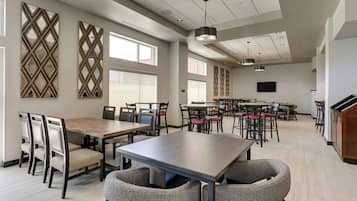 A spacious dining area with multiple tables and chairs, large windows, and decorative wall panels.