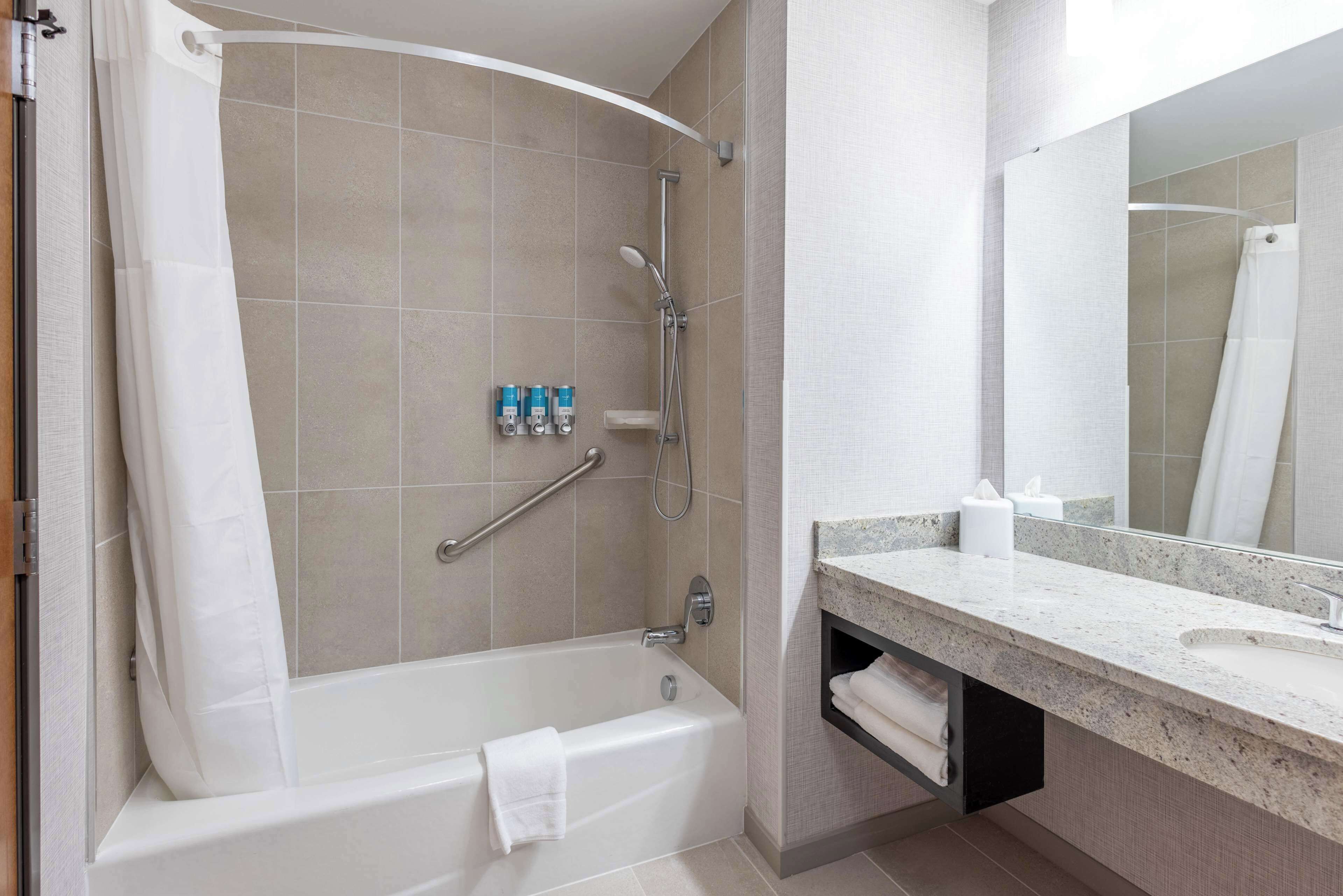 Ein modernes Badezimmer mit Badewanne, Dusche, Waschtisch und Spiegel.