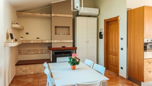 Eine Küche mit einem weißen Tisch und Stühlen, einem Blumentopf und einem Holzschrank.