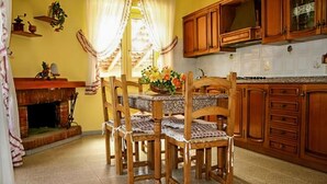Una cocina con armarios de madera, piso de baldosas y una mesa de comedor con sillas.