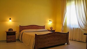 Un dormitorio con cama de madera, dos mesitas de noche y un ventanal con cortinas.