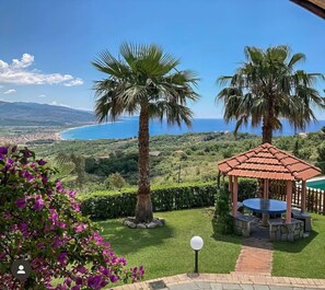 A gazebo with a tiled roof, surrounded by a well-maintained lawn and flowering plants. - Villa Fiorita - Casal Velino (Casal Velino)