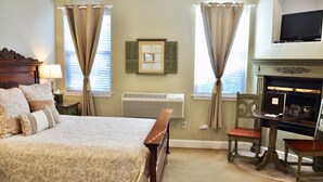 A bedroom with a bed, a chair, a fireplace, and a television. - Queen downstairs room (cayucos)
