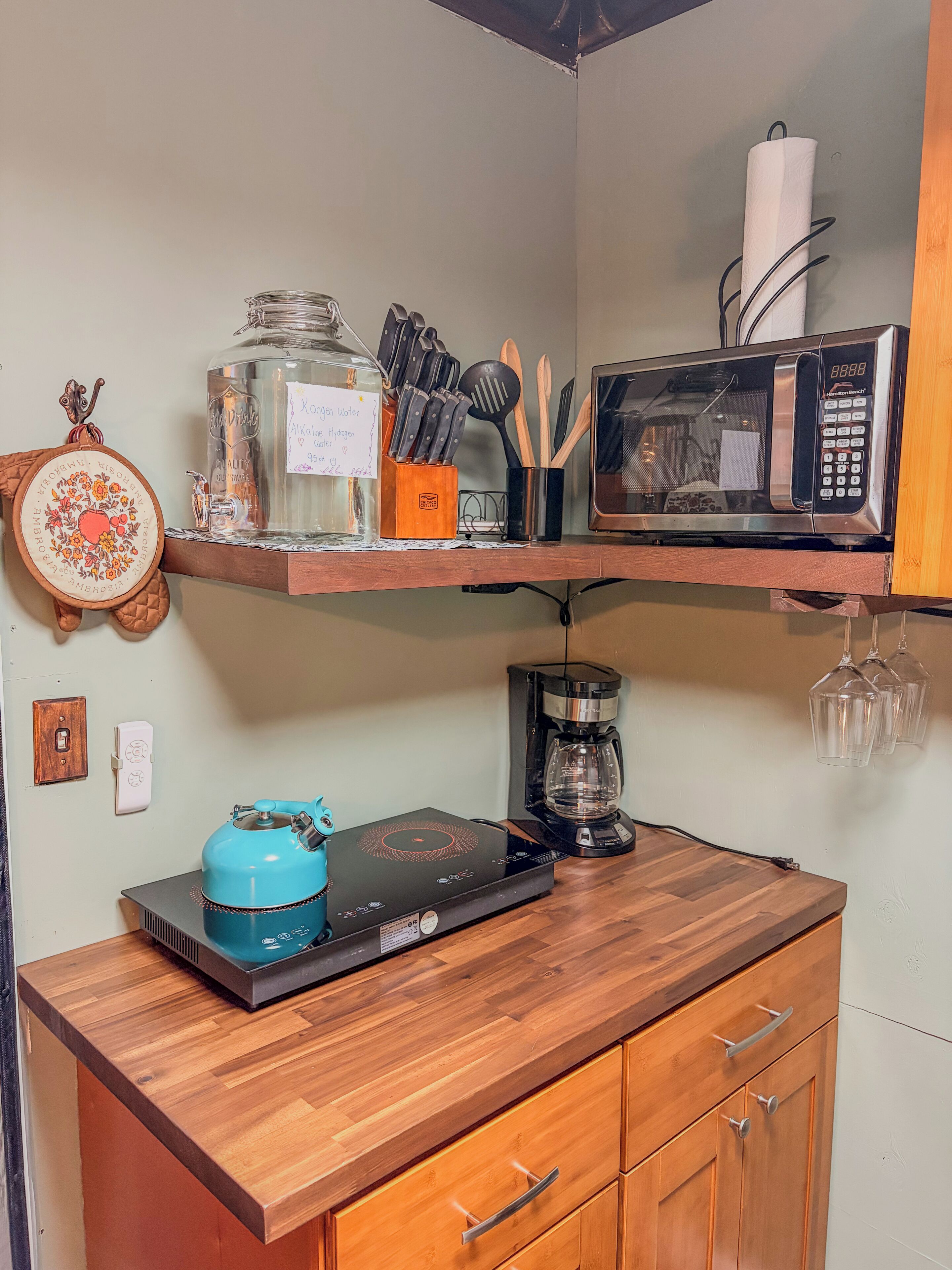 A kitchen with a coffee maker, microwave, and a blue induction cooktop.