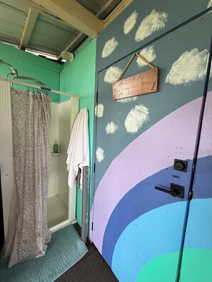 Un baño con ducha, un perchero y una puerta con un cartel.
